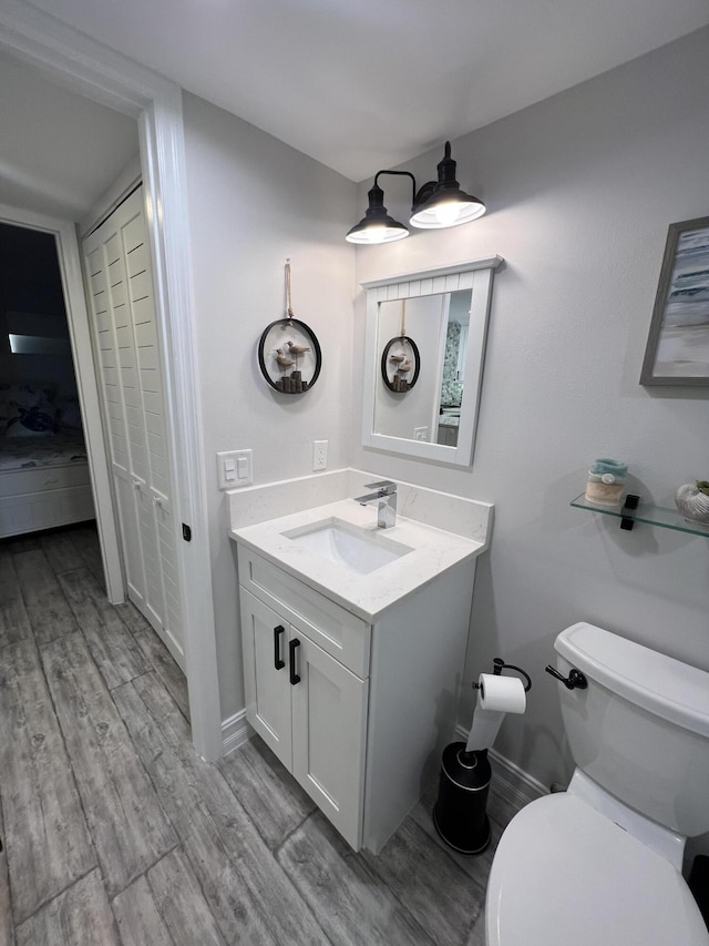 bathroom with baseboards, vanity, toilet, and wood finished floors