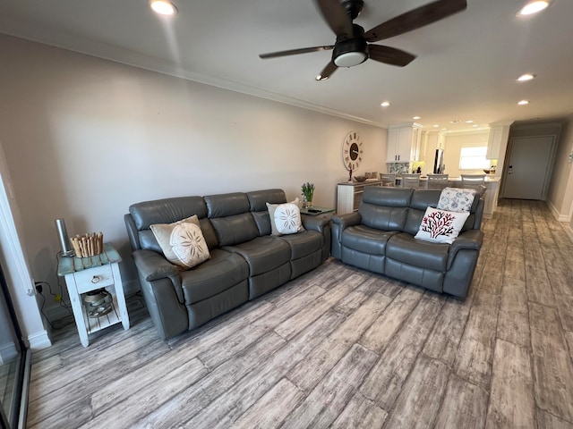 living room featuring ceiling fan, light hardwood / wood-style floors, and ornamental molding