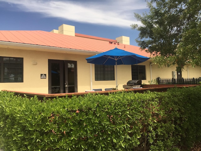 rear view of property with metal roof, french doors, and stucco siding