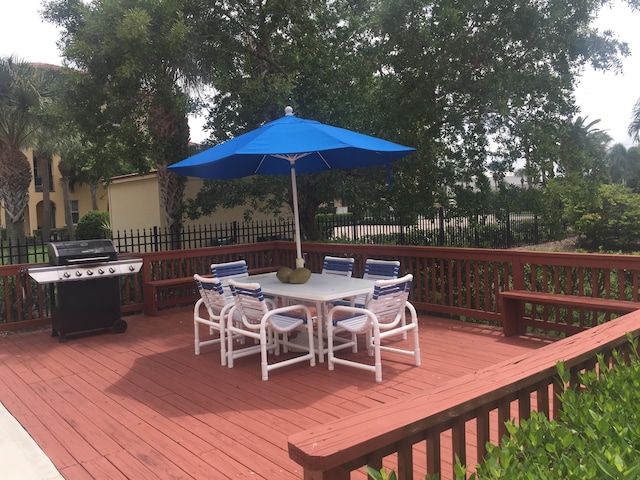 wooden deck with outdoor dining area, fence, and grilling area