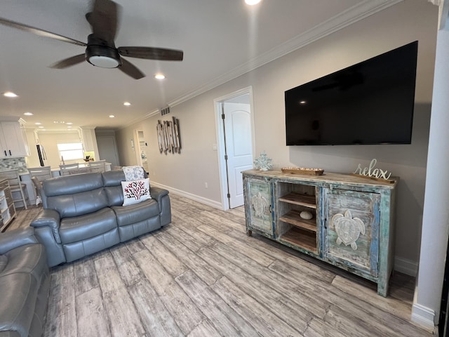 living area with light wood finished floors, baseboards, ceiling fan, ornamental molding, and recessed lighting