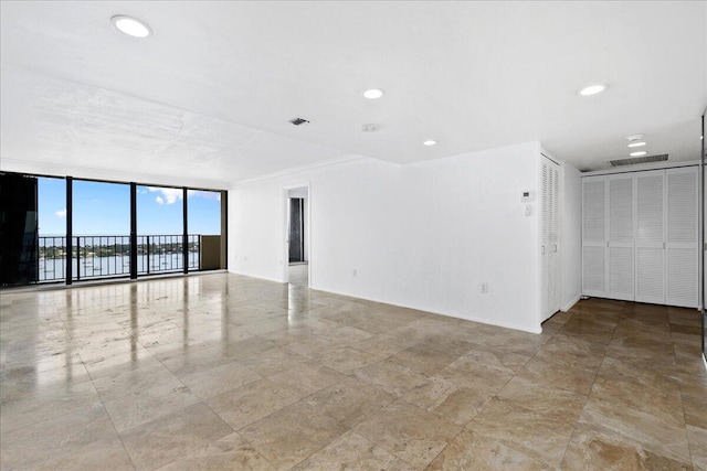 tiled empty room with expansive windows and crown molding