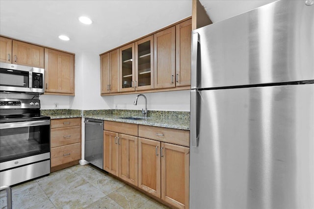 kitchen featuring stone counters, sink, light tile patterned floors, and stainless steel appliances