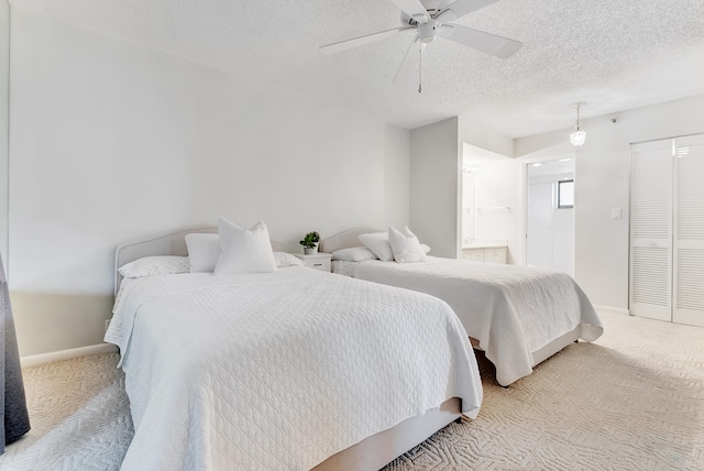 carpeted bedroom featuring connected bathroom, a textured ceiling, a closet, and ceiling fan