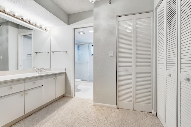 bathroom featuring vanity, a textured ceiling, and toilet