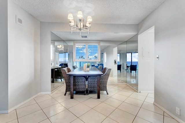 dining space featuring a healthy amount of sunlight, a notable chandelier, light tile patterned floors, and a textured ceiling