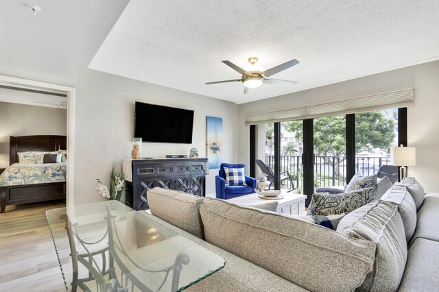 living room featuring a textured ceiling, ceiling fan, and light hardwood / wood-style floors