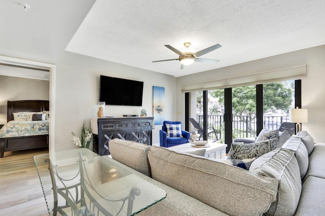 living room with ceiling fan, light hardwood / wood-style flooring, and a textured ceiling