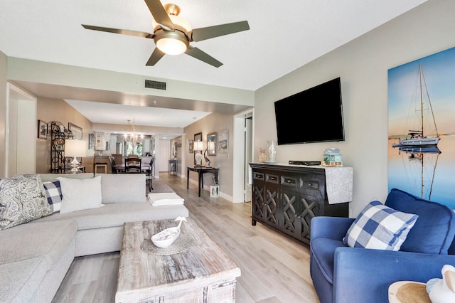 living room featuring light hardwood / wood-style flooring and ceiling fan with notable chandelier