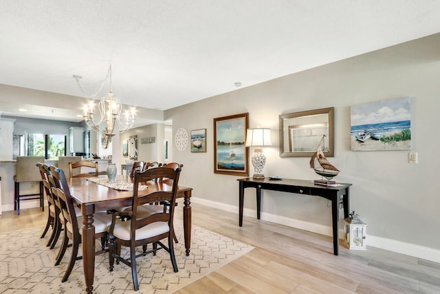 dining space featuring a notable chandelier and light wood-type flooring