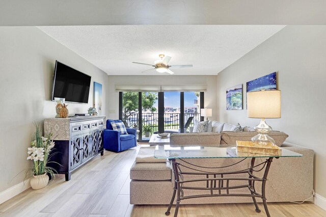 living room featuring a textured ceiling, ceiling fan, and light hardwood / wood-style floors