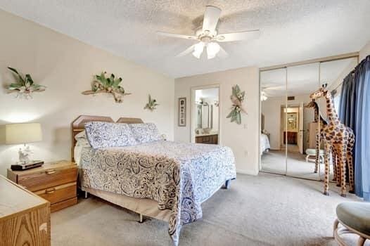 bedroom with a closet, carpet, ceiling fan, ensuite bathroom, and a textured ceiling