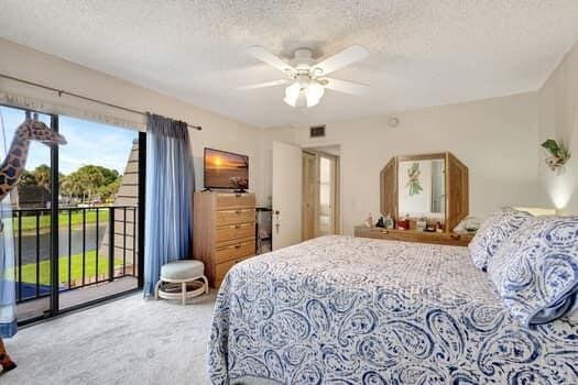 carpeted bedroom featuring ceiling fan, access to exterior, and a textured ceiling