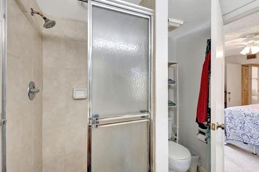 bathroom featuring toilet, an enclosed shower, and ceiling fan