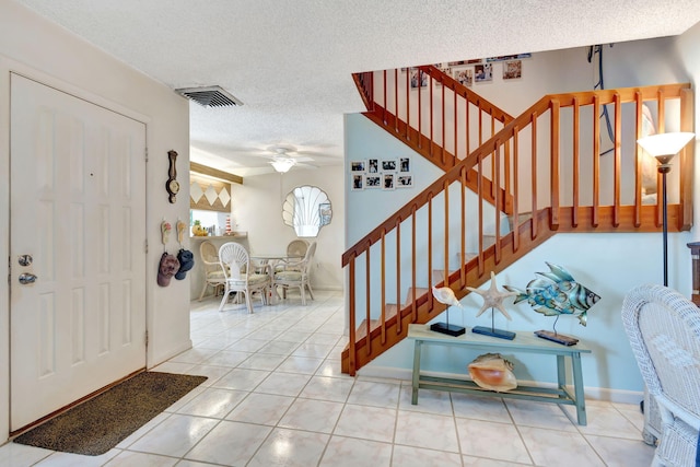 tiled entrance foyer with ceiling fan and a textured ceiling