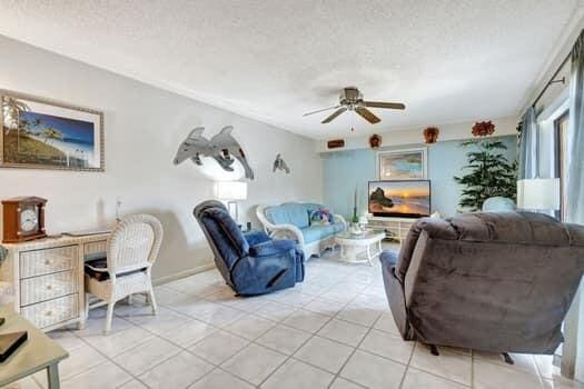 tiled living room featuring a textured ceiling and ceiling fan