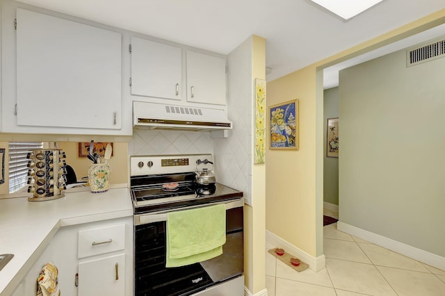 kitchen with tasteful backsplash, stainless steel electric stove, light tile patterned flooring, and white cabinets