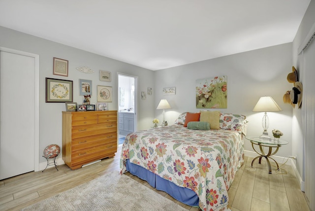 bedroom with ensuite bath and light wood-type flooring