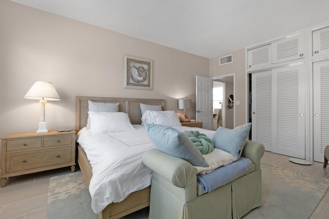 bedroom featuring light wood-style floors, visible vents, and a closet