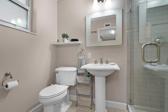 bathroom featuring tile patterned flooring, toilet, a shower with door, and sink