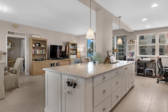 kitchen with a center island, visible vents, hanging light fixtures, open floor plan, and white cabinetry