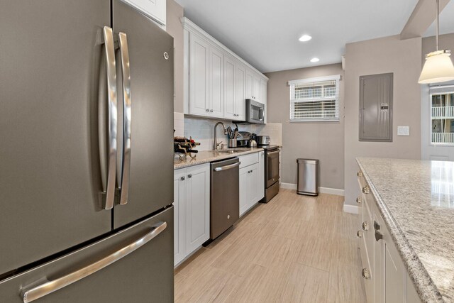 kitchen featuring appliances with stainless steel finishes, sink, white cabinets, electric panel, and hanging light fixtures