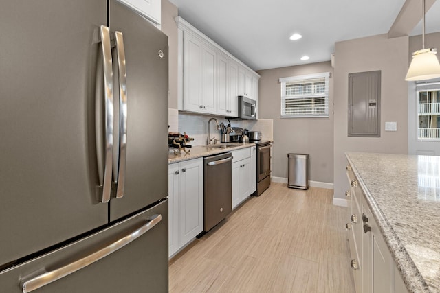 kitchen featuring electric panel, white cabinets, appliances with stainless steel finishes, decorative light fixtures, and a sink