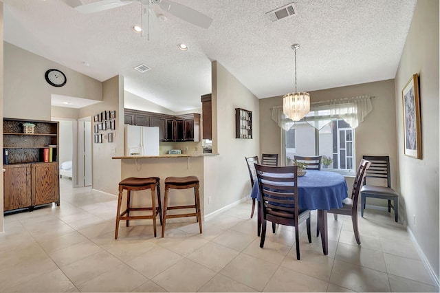 tiled dining space with vaulted ceiling, a textured ceiling, and ceiling fan with notable chandelier