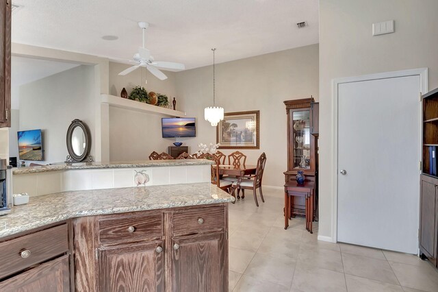 kitchen with ceiling fan, decorative light fixtures, light stone countertops, and light tile patterned floors