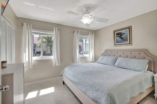 tiled bedroom with a textured ceiling, a closet, and ceiling fan