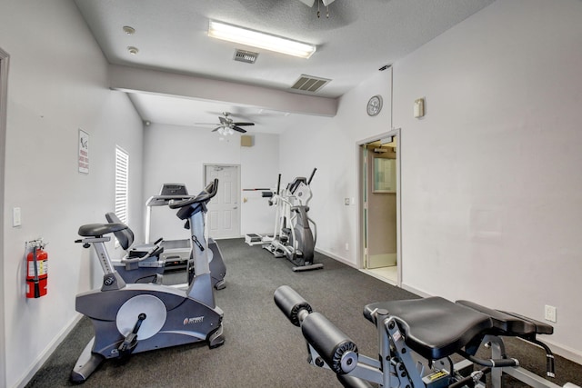 workout area featuring ceiling fan, carpet, and a textured ceiling