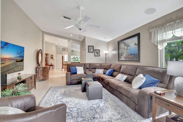 living room featuring ceiling fan, vaulted ceiling, a textured ceiling, and light tile patterned floors