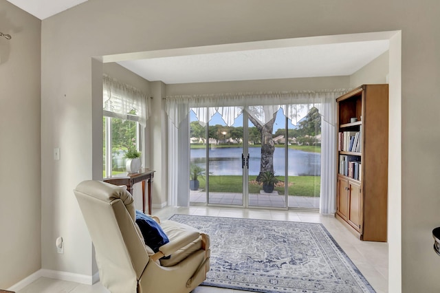 living area with light tile patterned flooring and a water view