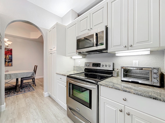 kitchen featuring appliances with stainless steel finishes, white cabinetry, light stone counters, and light hardwood / wood-style floors