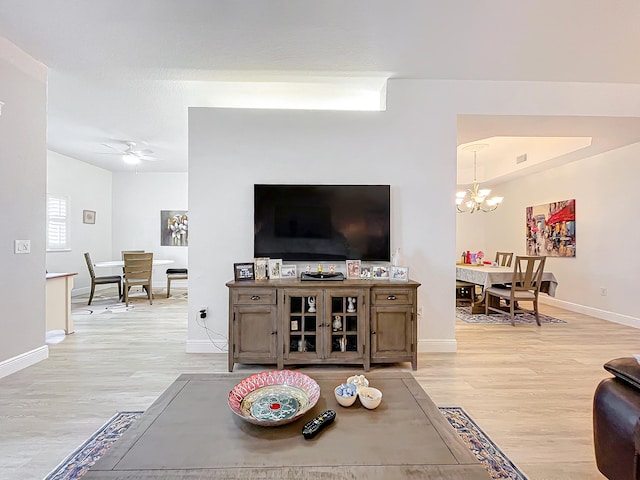 living room with ceiling fan with notable chandelier and light wood-type flooring