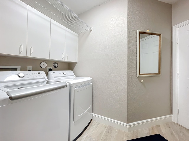 laundry room featuring cabinets, light wood-type flooring, and independent washer and dryer