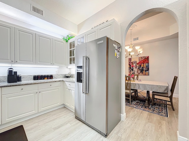 kitchen with white cabinets, an inviting chandelier, high end fridge, and light hardwood / wood-style floors