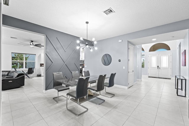 dining space featuring ceiling fan with notable chandelier and a textured ceiling