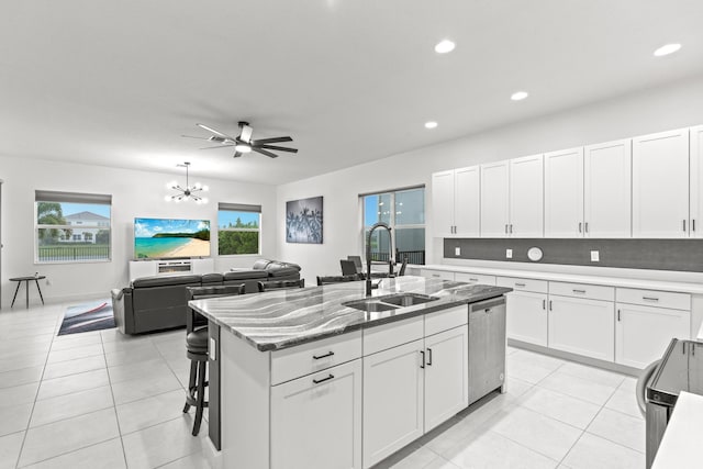 kitchen with sink, light tile patterned floors, dishwasher, white cabinetry, and an island with sink