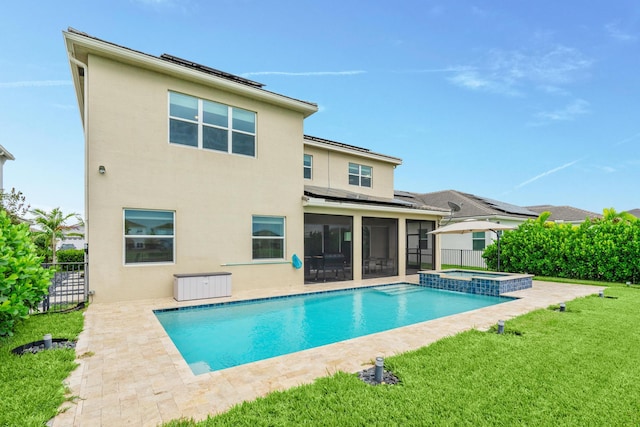 rear view of property with a yard, a swimming pool with hot tub, and a patio