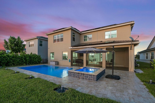 back house at dusk with a patio area, a yard, and a pool with hot tub