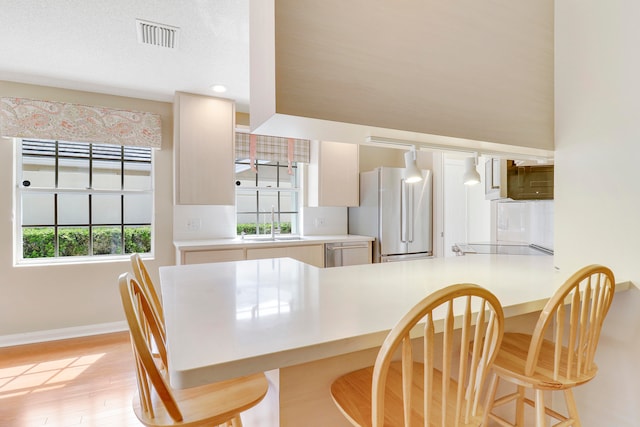 dining area with light hardwood / wood-style flooring, a wealth of natural light, a textured ceiling, and sink