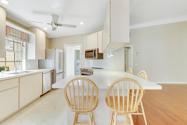 kitchen with light hardwood / wood-style flooring, stainless steel appliances, ceiling fan, sink, and vaulted ceiling