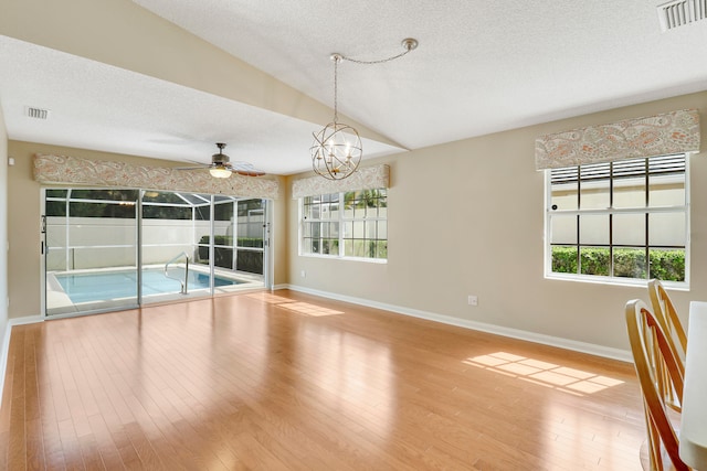 interior space with vaulted ceiling, a textured ceiling, a healthy amount of sunlight, and hardwood / wood-style floors