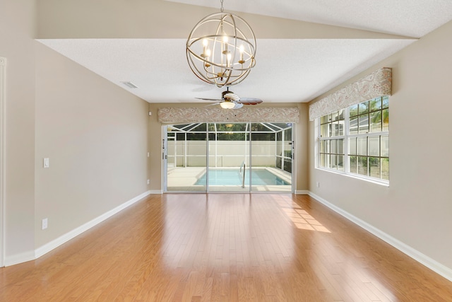 unfurnished room featuring lofted ceiling, a textured ceiling, light hardwood / wood-style flooring, and ceiling fan with notable chandelier