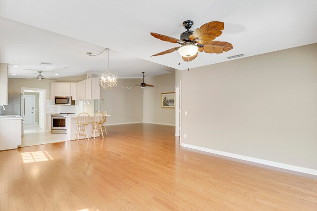 unfurnished living room with light hardwood / wood-style flooring and ceiling fan with notable chandelier