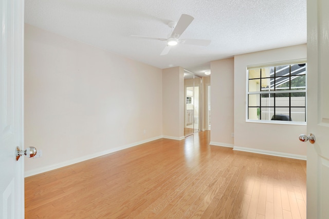 unfurnished room with a textured ceiling, light wood-type flooring, and ceiling fan