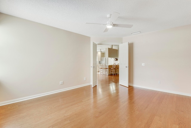 empty room featuring ceiling fan, a textured ceiling, and light hardwood / wood-style floors