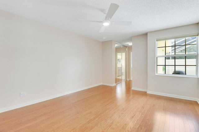 unfurnished room with a textured ceiling, light wood-type flooring, and ceiling fan