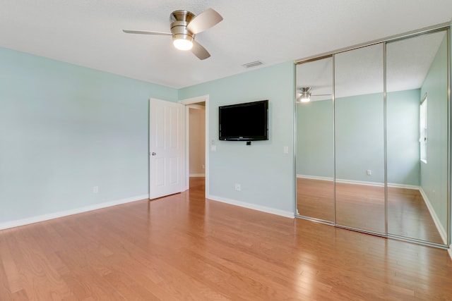 unfurnished bedroom with ceiling fan, hardwood / wood-style flooring, and a closet